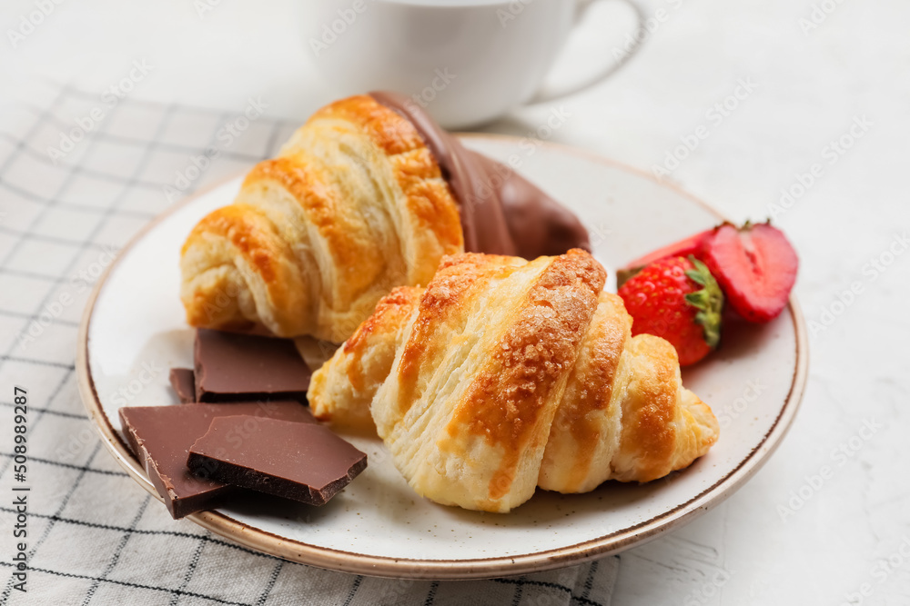 Plate of Delicious croissants with strawberry and chocolate on light background