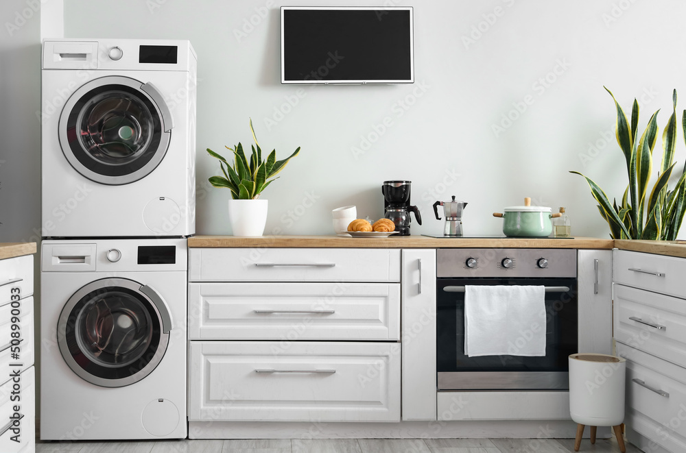 Stylish interior of kitchen with modern washing machines