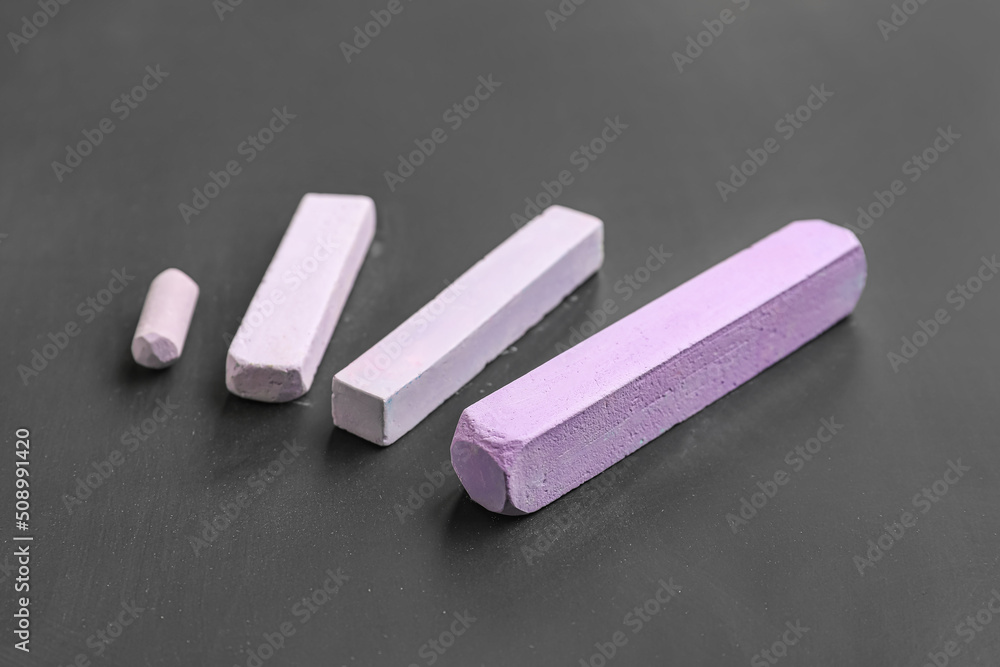 Pieces of lilac chalk on blackboard, closeup