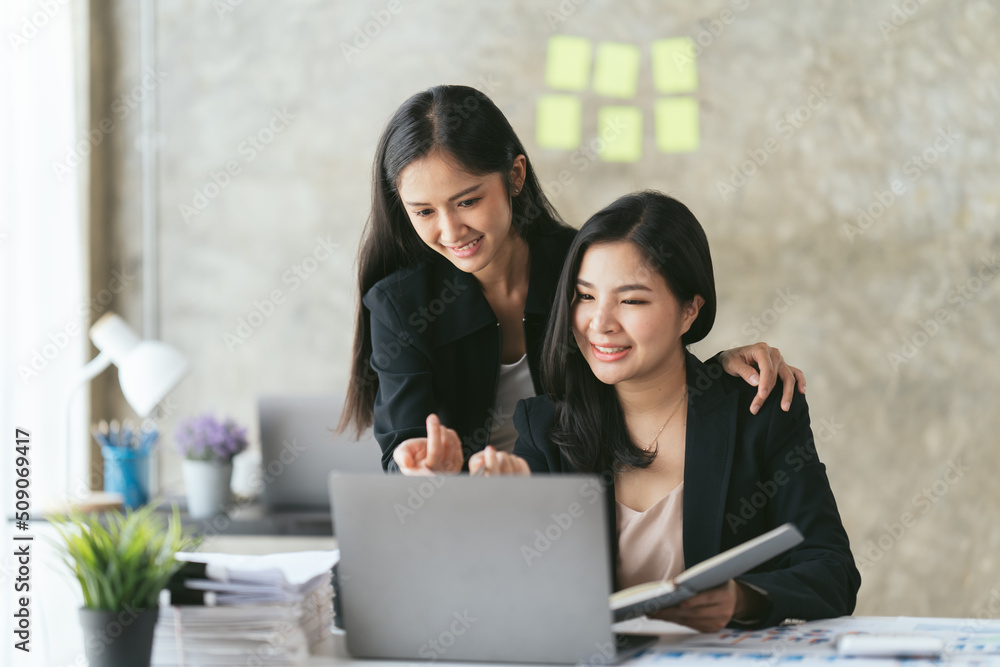 Group of young asian business people discussing something and smiling while sitting at the office ta