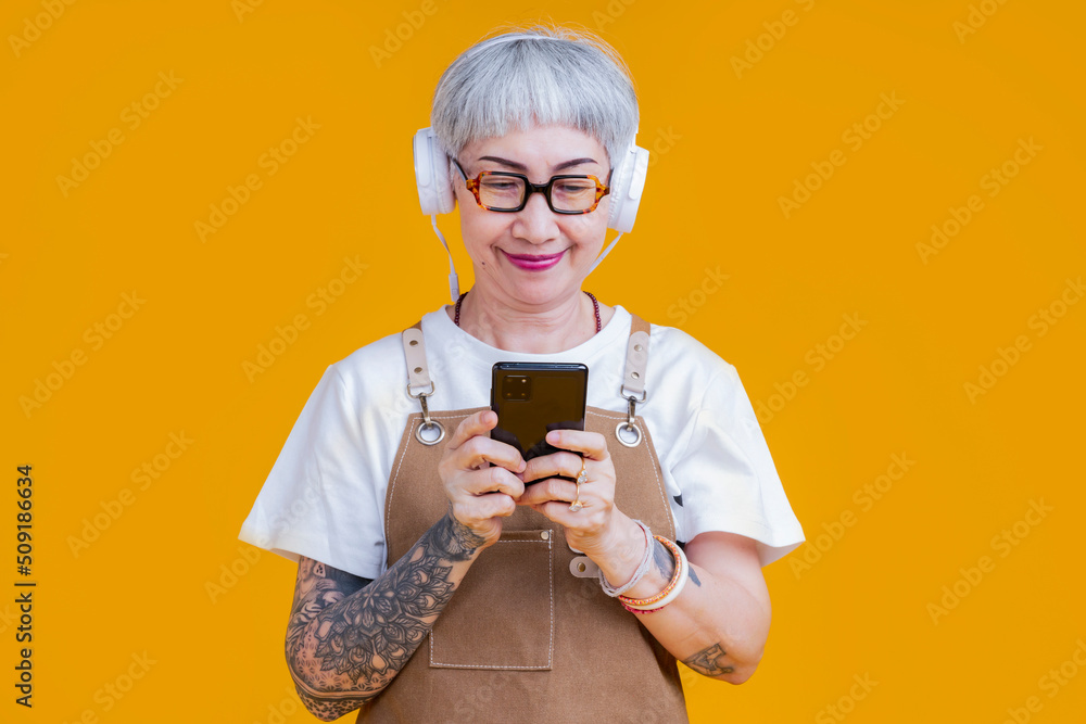 old senior asian woman wear apron hand choosing music playlist from smartphone relax casual lifestyl