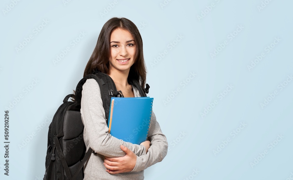 背着背包，手里拿着书的年轻女学生