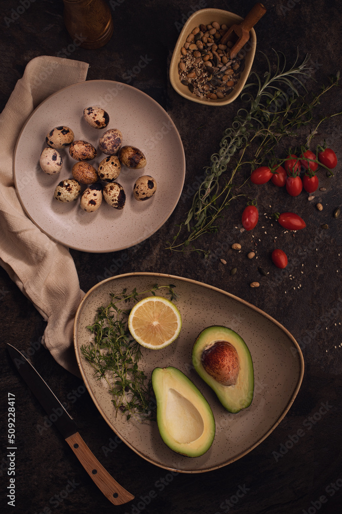 Ripe avacado decoreted on the plate and raw Quail eggs on the dark table.Healthy breakfast, vegetabl