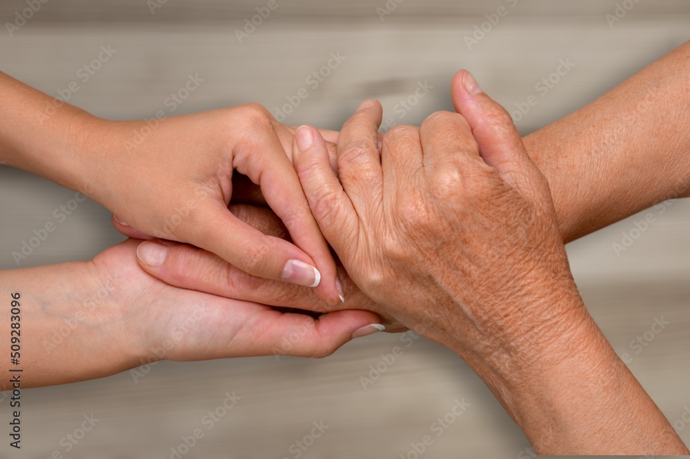 Support hands. young woman holding a senior mans hands in comfort. Female carer holding hands of se