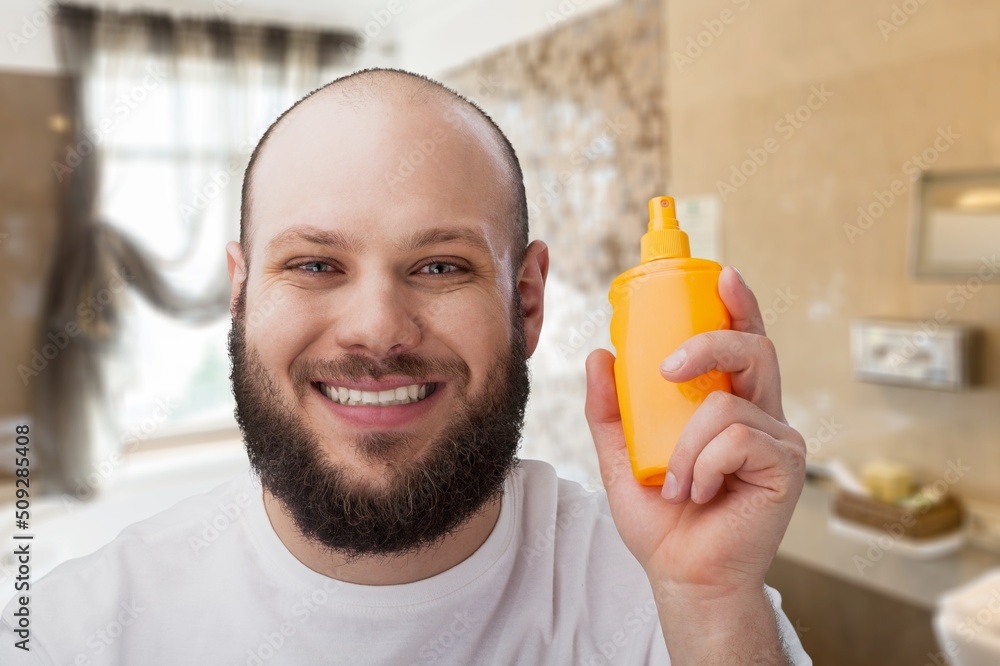 Young guy using serum for hair growth in bathroom