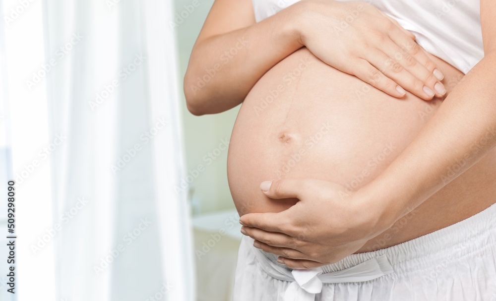 A young pregnant woman touching her belly and caring about her health