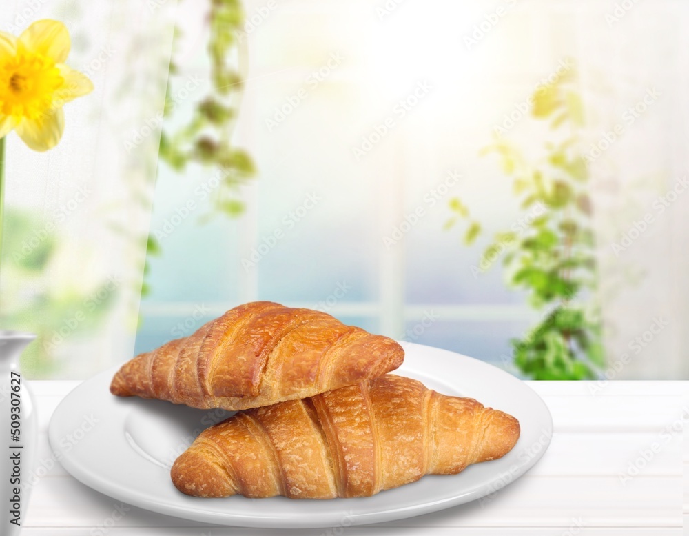 Croissants in white plate on the kitchen background