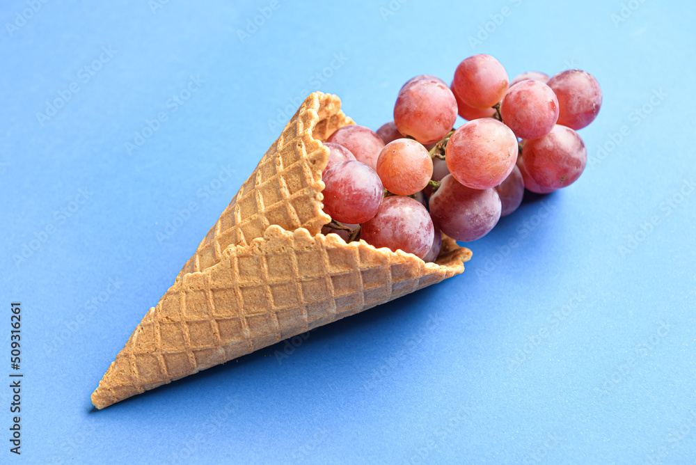 Wafer cone with fresh grapes on color background