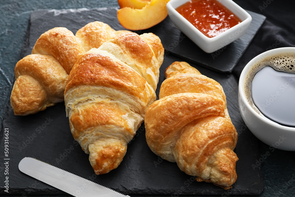 Board of delicious croissants on black background