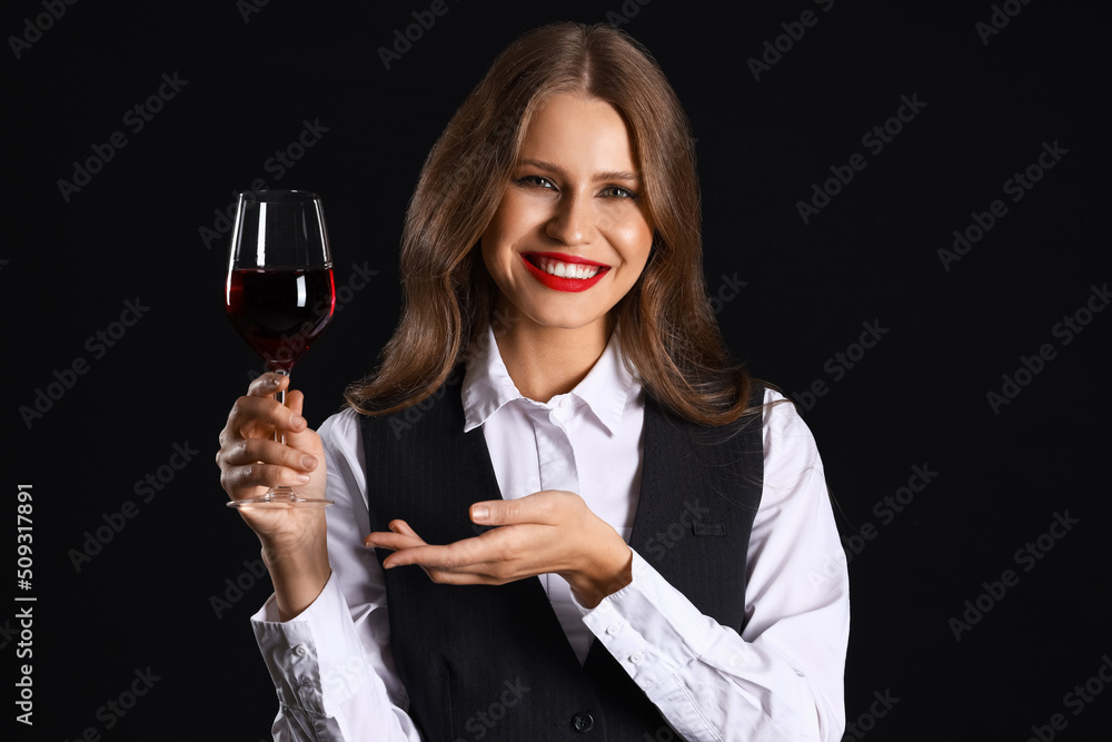 Beautiful female sommelier with wine on black background