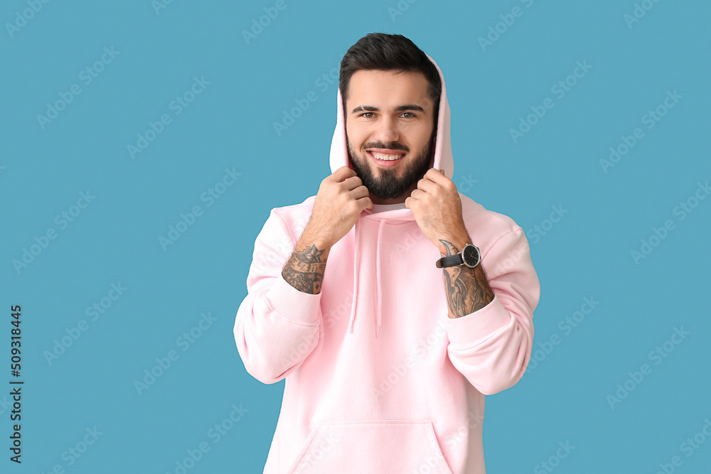 Young bearded man wearing stylish hoodie on blue background