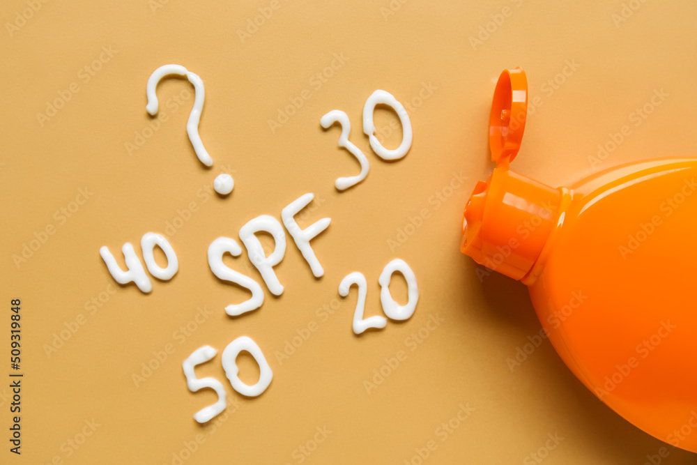 Question SPF? and numbers made with sunscreen cream on orange background