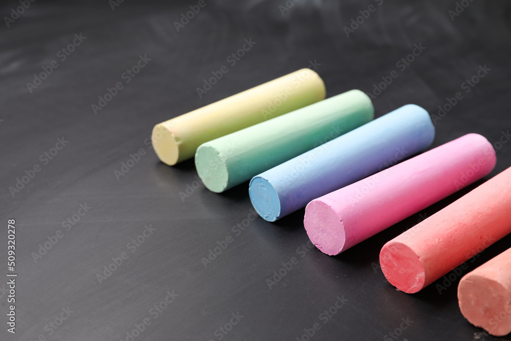 Colorful chalks on blackboard, closeup