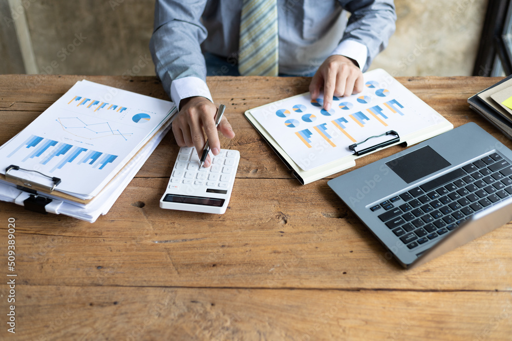 Businessman working on desk office with using a calculator to calculate the finance numbers and calc