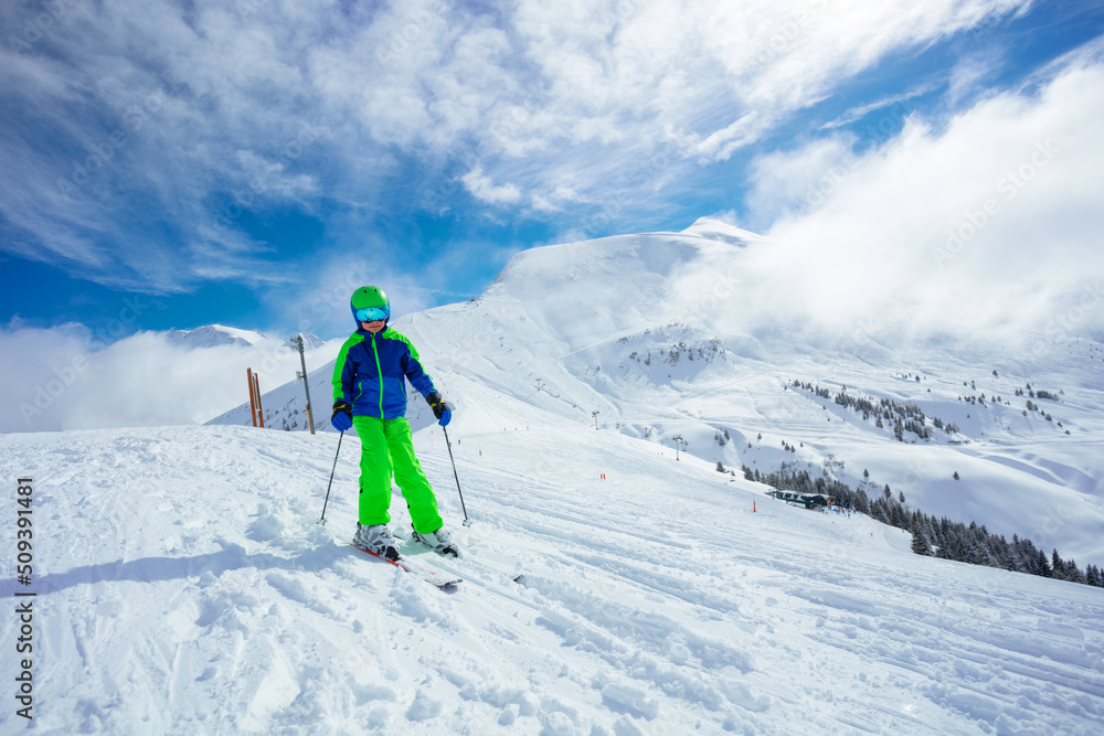 Preteen handsome boy ski downhill on mountain slope