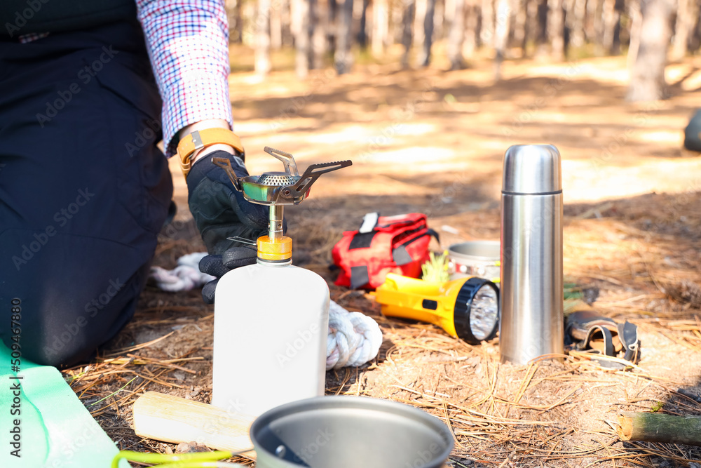 Male tourist with portable gas burner in forest