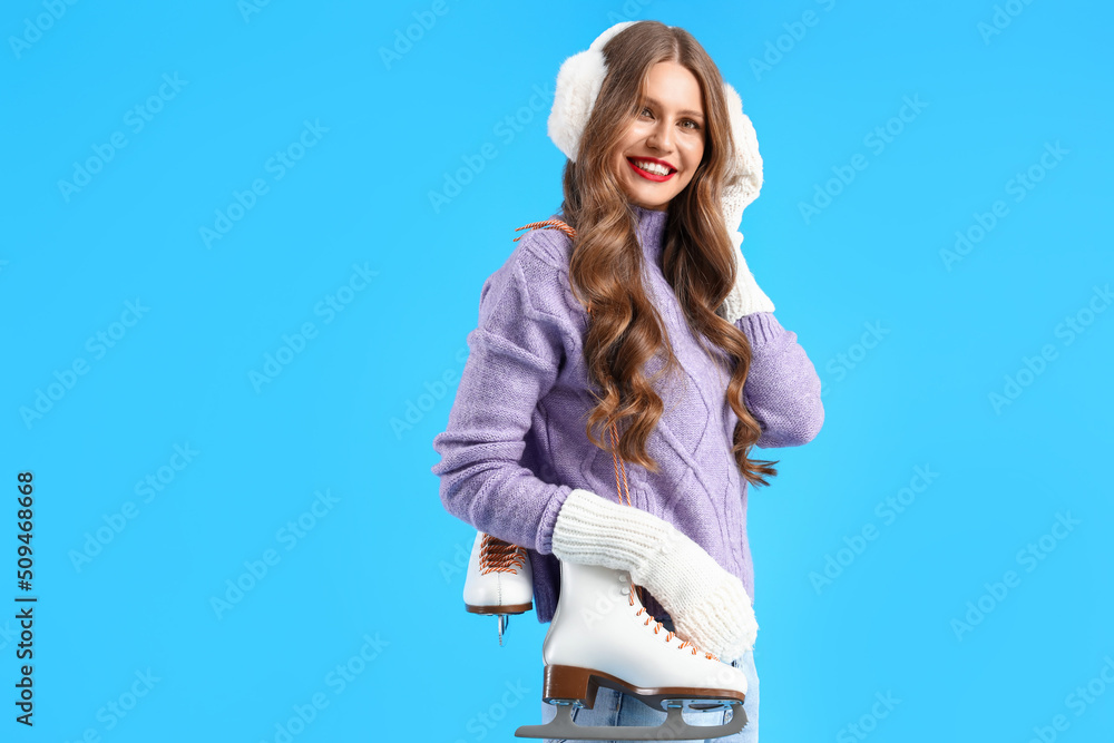 Beautiful young woman with ice skates on blue background