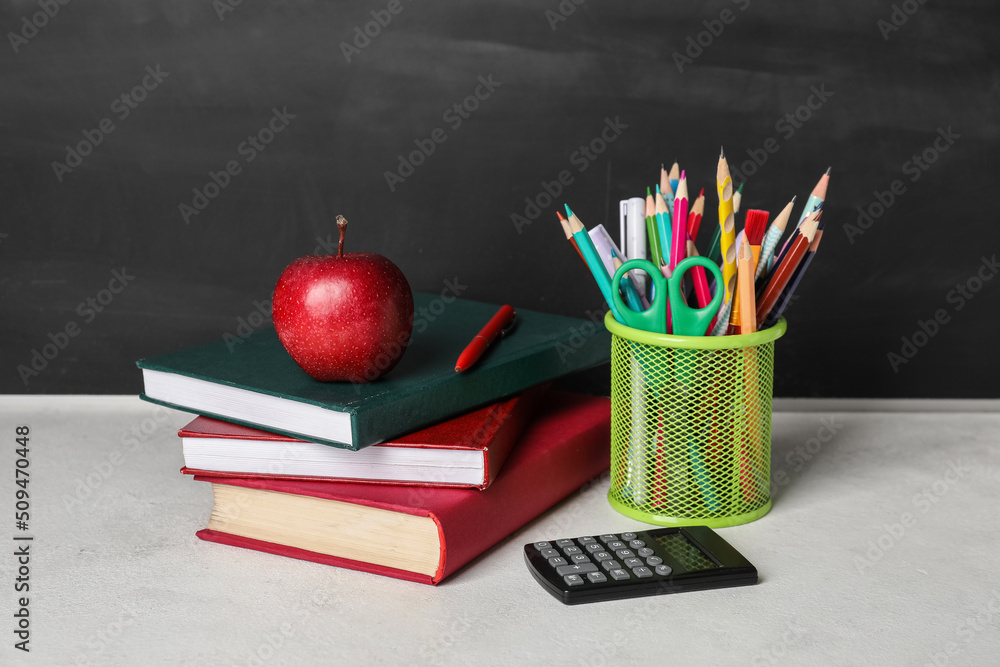 School stationery with apple on table near blackboard