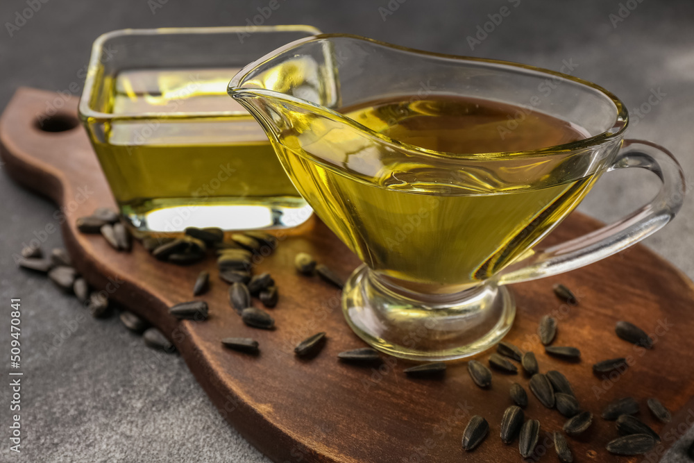 Board with oil and sunflower seeds on dark background, closeup