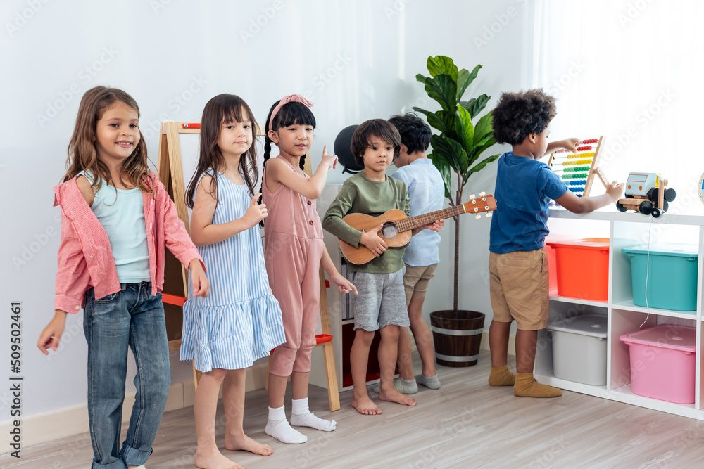 Group of Mixed race young little kid playing guitar in schoolroom