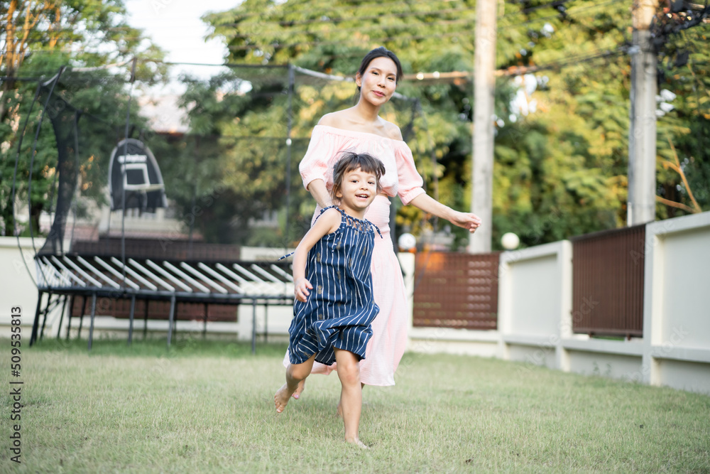 亚洲孕妇带着年幼的女儿在后院户外玩耍。