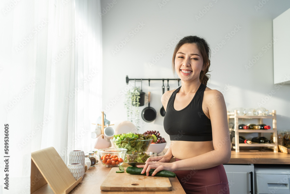 亚洲美女烹饪沙拉的肖像，看着镜头。