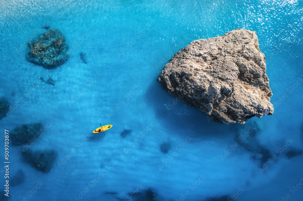 Aerial view of yellow kayak in blue sea at sunset in summer. Man on floating canoe in clear azure wa