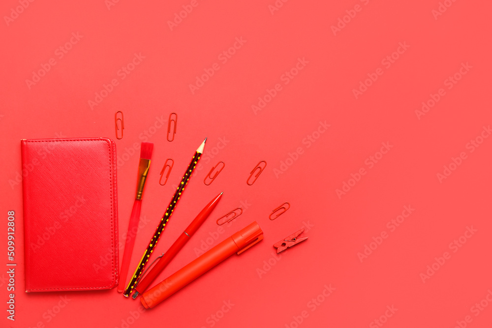 Paper clips with stationery on red background