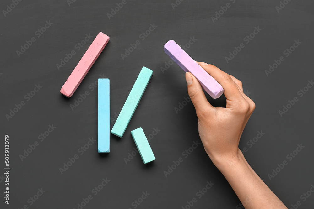 Woman with colorful chalks on blackboard, top view