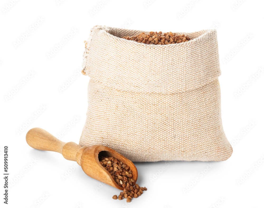 Cloth bag and wooden scoop with buckwheat grains on white background