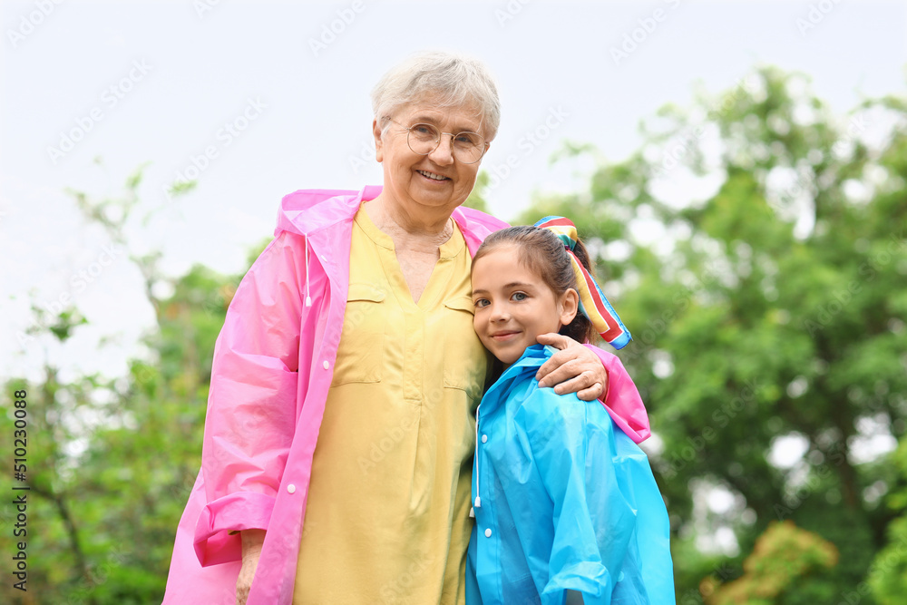 穿着雨衣的小女孩和奶奶在户外拥抱