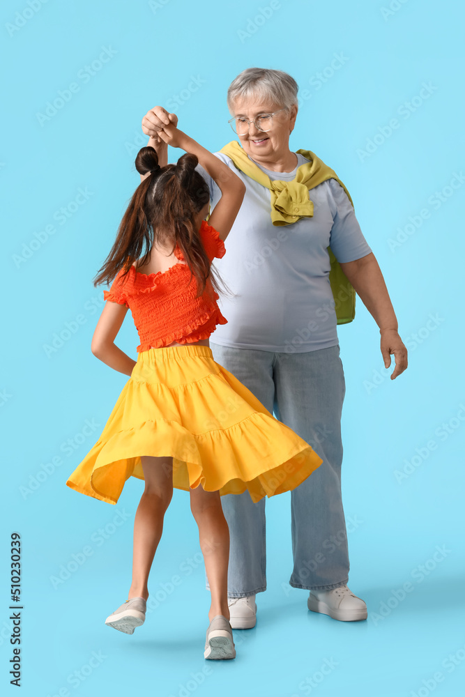 Little girl with her grandma dancing on blue background