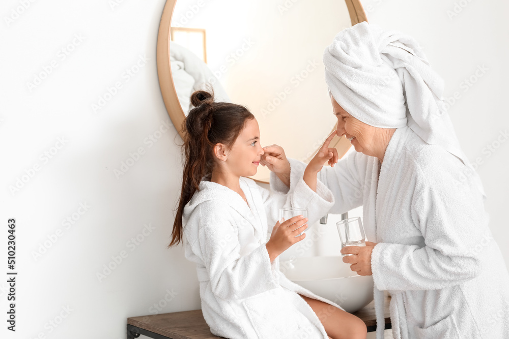 Little girl and her grandma touching each others noses in bathroom