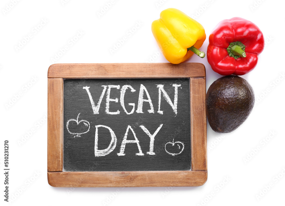 Board with text VEGAN DAY and vegetables on white background