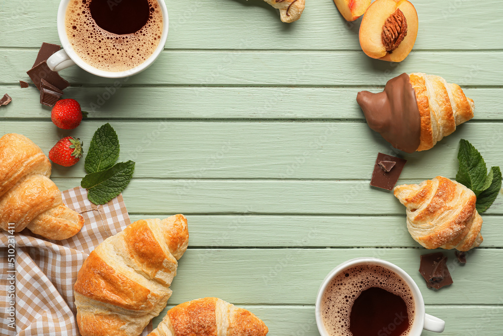 Frame made of tasty croissants, different fruits and cups with coffee on green wooden background