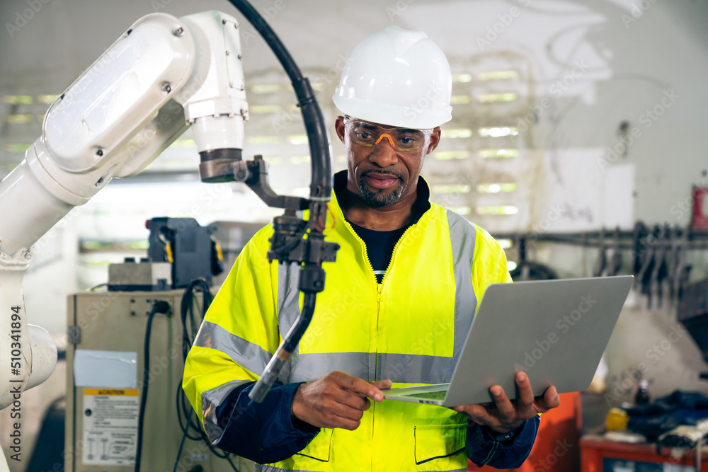 African American factory worker working with adept robotic arm in a workshop . Industry robot progra