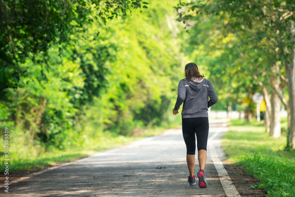 Asian  woman in sportswear Jogging running  at park in sunshine beautiful  day