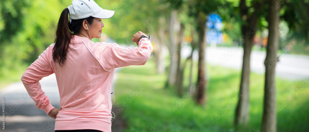 穿着运动服的亚洲女子在公园慢跑前看手表检查心率