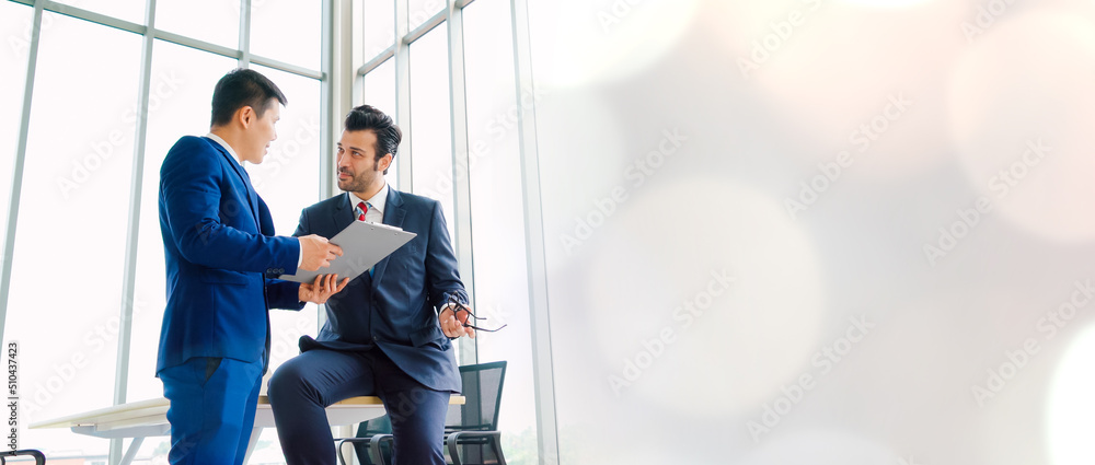 Two business people talk project strategy at office in widen view meeting room. Businessman discuss 