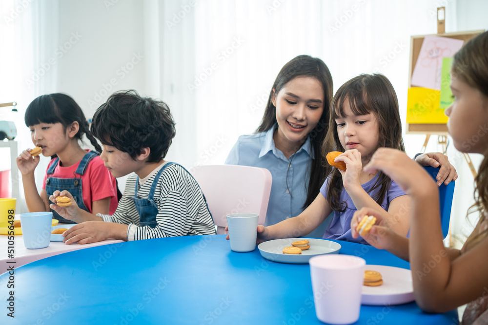 亚洲漂亮的年轻女老师在教室里给孩子们端零食。