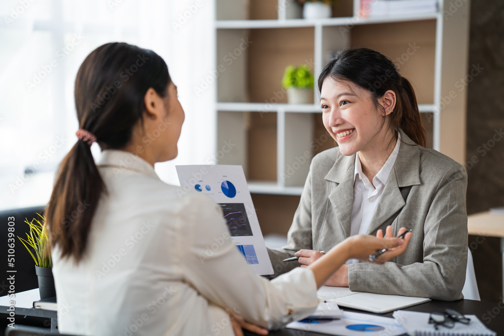 两位女商人在现代办公室举行非正式会议，导师帮助学徒解释公司