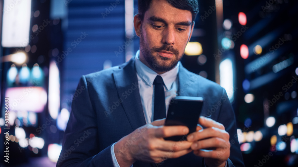 Portrait of a Handsome Man in Stylish Suit Walking in a Modern City Street with Neon Lights at Night