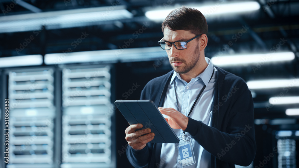 Male IT Specialist Walks Between Row of Operational Server Racks in Data Center. Engineer Uses Table