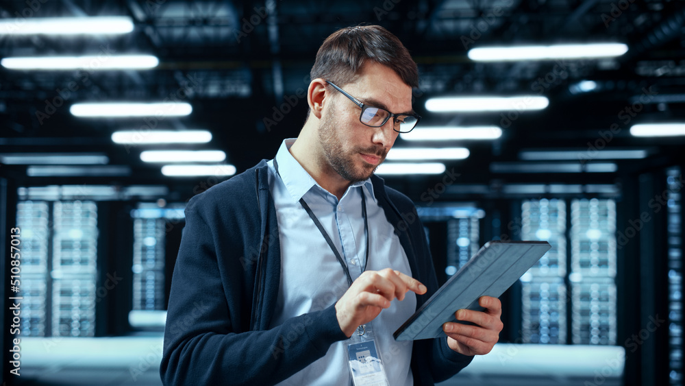 Portrait of a Bearded Handsome Caucasian IT Engineer in Glasses Standing with Tablet and Posing in t