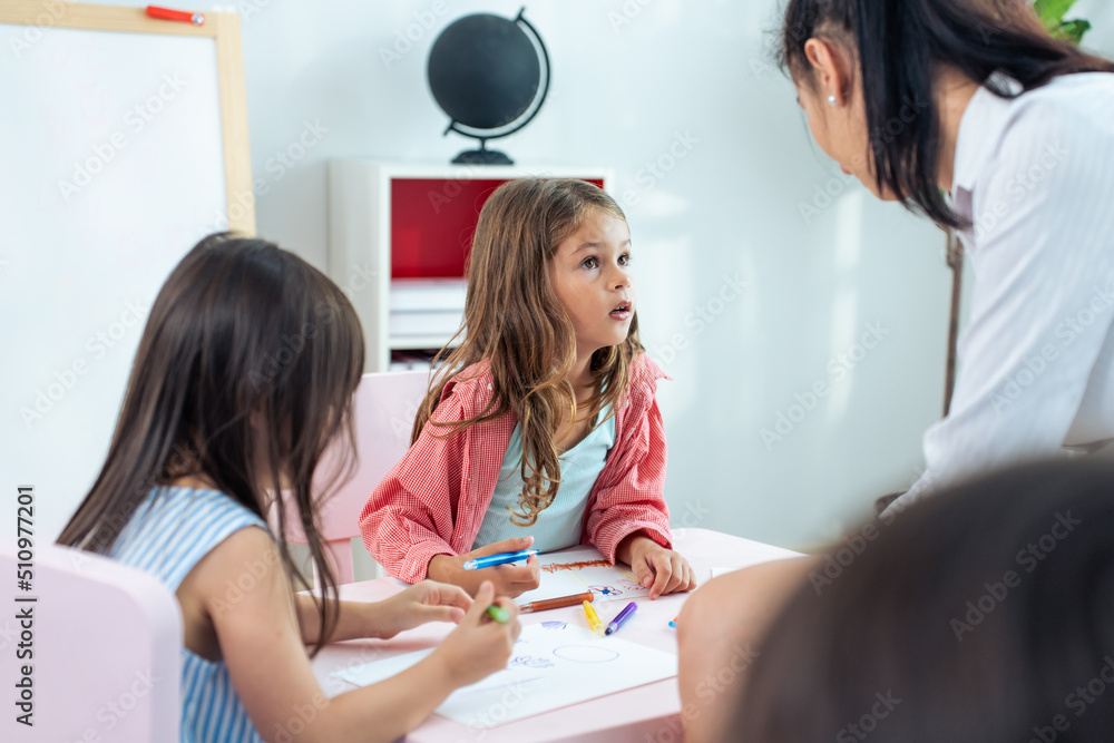 Caucasian beautiful woman teacher teaching a lesson to kid at school. 