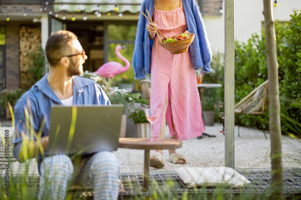 Happy young family with laptop and healthy lunch at backyard