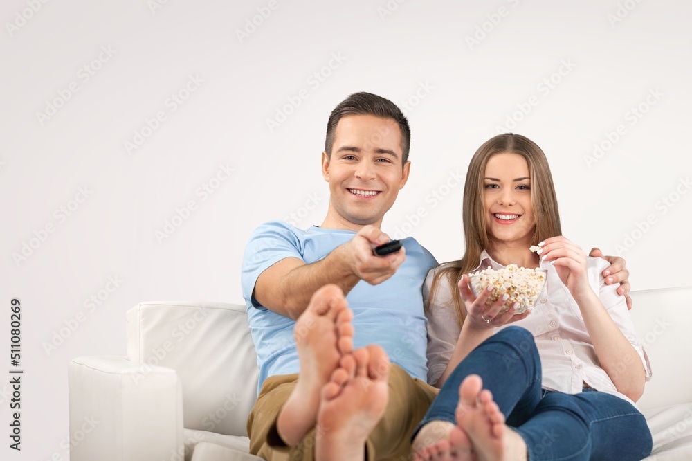 Portrait of couple watching TV show or film, holding remote control, switching channels.