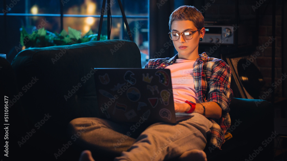 Young Beautiful Woman Resting on Couch, Using Laptop Computer in Stylish Loft Apartment in the Eveni