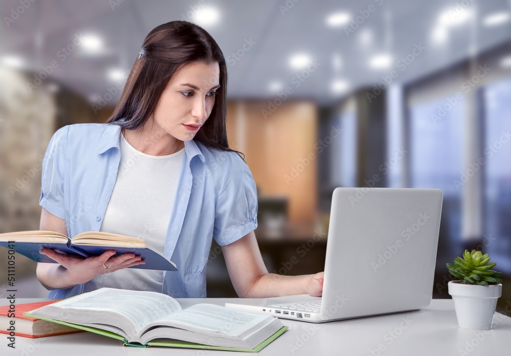 Business And Education Concept. Smiling young woman sitting at desk working on laptop