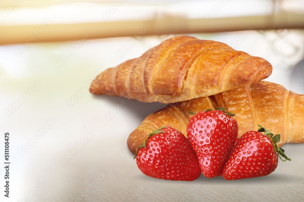 Tasty sweet Croissant with fresh strawberry on the desk